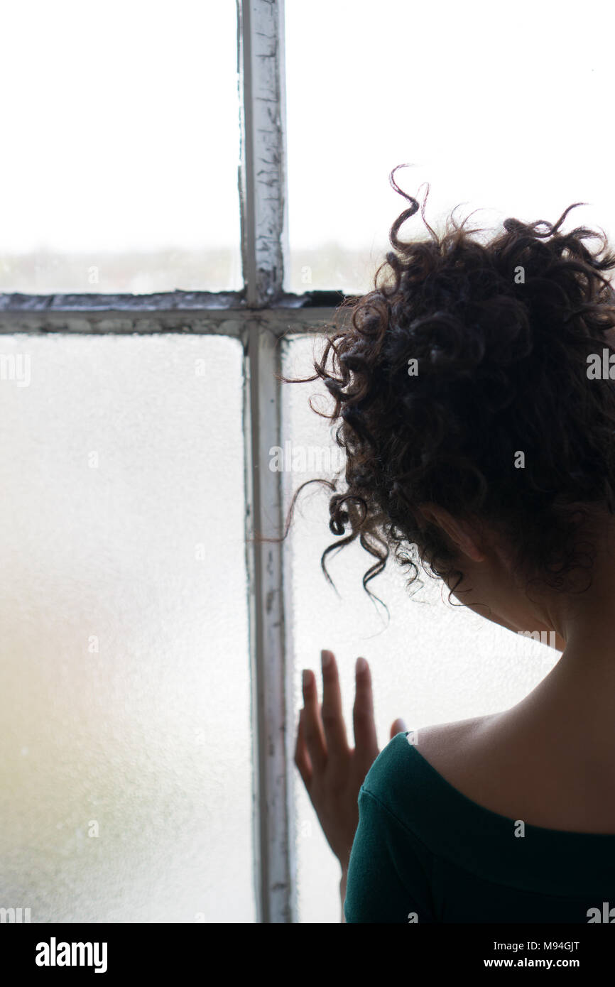 Rückansicht eines traurige junge Frau, die am Fenster Stockfoto