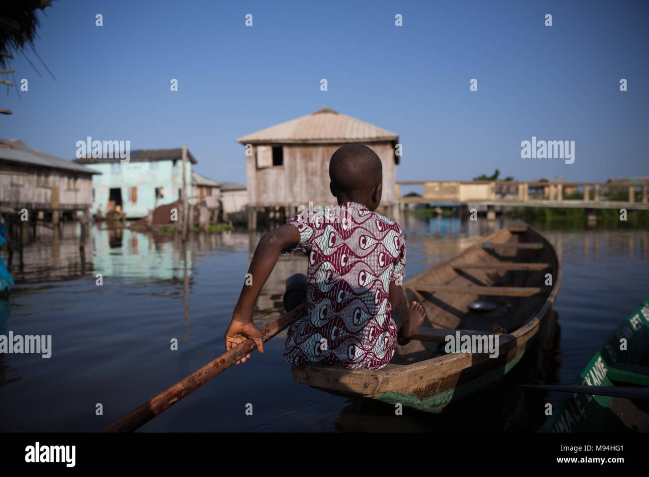 Ein junger Bewohner von Ganvie, im See Nokoué, Paddel sein Boot durch das Dorf. Ganvie ist wahrscheinlich die größte Neigung' Dorf in Afrika, mit einer Bevölkerung von etwa 20.000 Menschen. Süden von Benin. Stockfoto