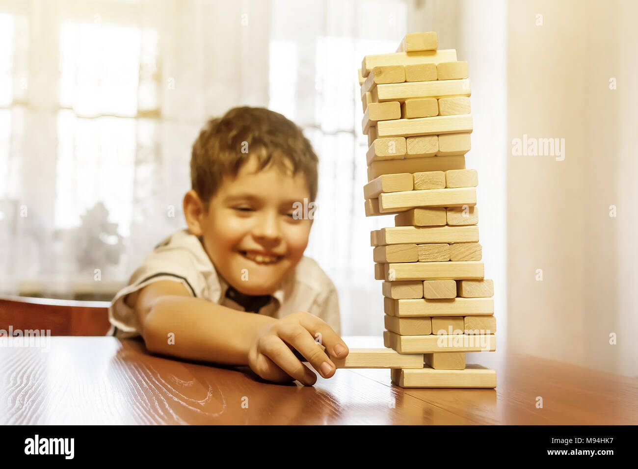 Junge spielt Holz Tower Spiel auf Holztisch. Die hohen hölzernen Turm von Blöcken fällt. Stockfoto