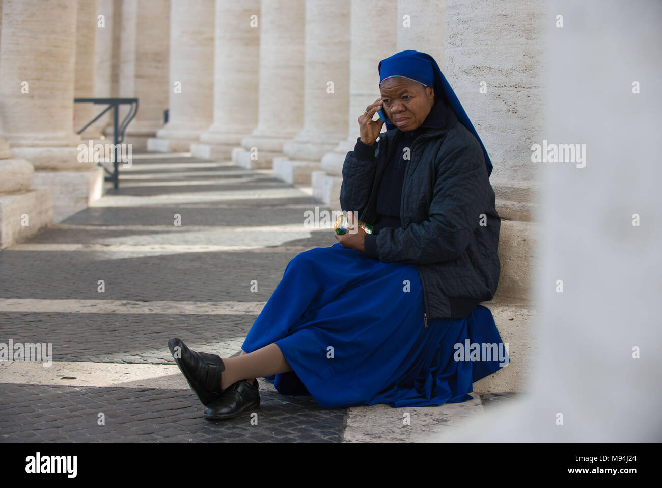 Vatikanstadt. Afrikanische Nonne sitzen entlang Bernini columnade, St. Peter's Square. Vatikan. Stockfoto