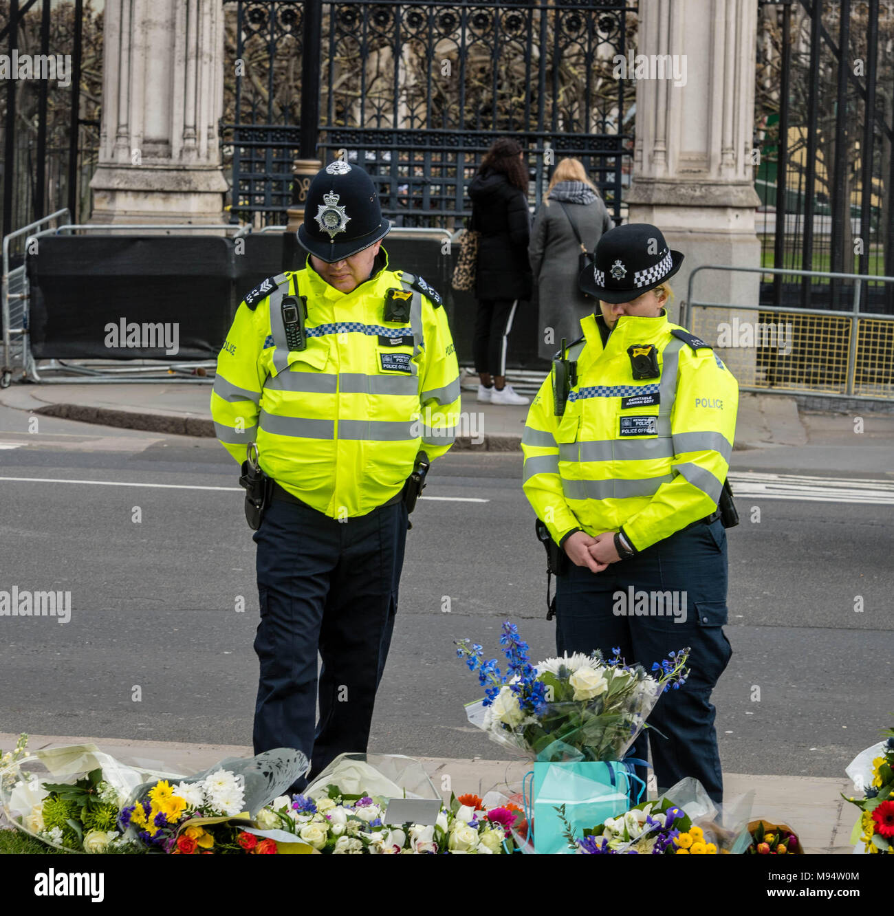 London, Großbritannien. 22. März 2018 Zwei Polizisten an der Blumen außerhalb des House of Commons zum Gedenken an den 1. Jahrestag der Westminster Terroranschlag aussehen. Credit: Ian Davidson/Alamy leben Nachrichten Stockfoto