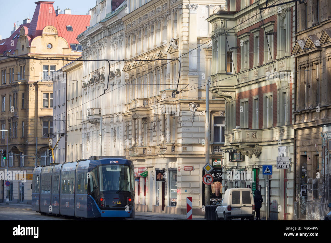 Das reflektierte Licht von einem in der Nähe gelegenen Platte Glas Gebäude, beleuchtet ältere Architektur und eine Straßenbahn auf Dukelskych hrdinu Straße, Stadtteil Holesovice, Prag 7, am 19. März 2018, in Prag, Tschechische Republik. Stockfoto