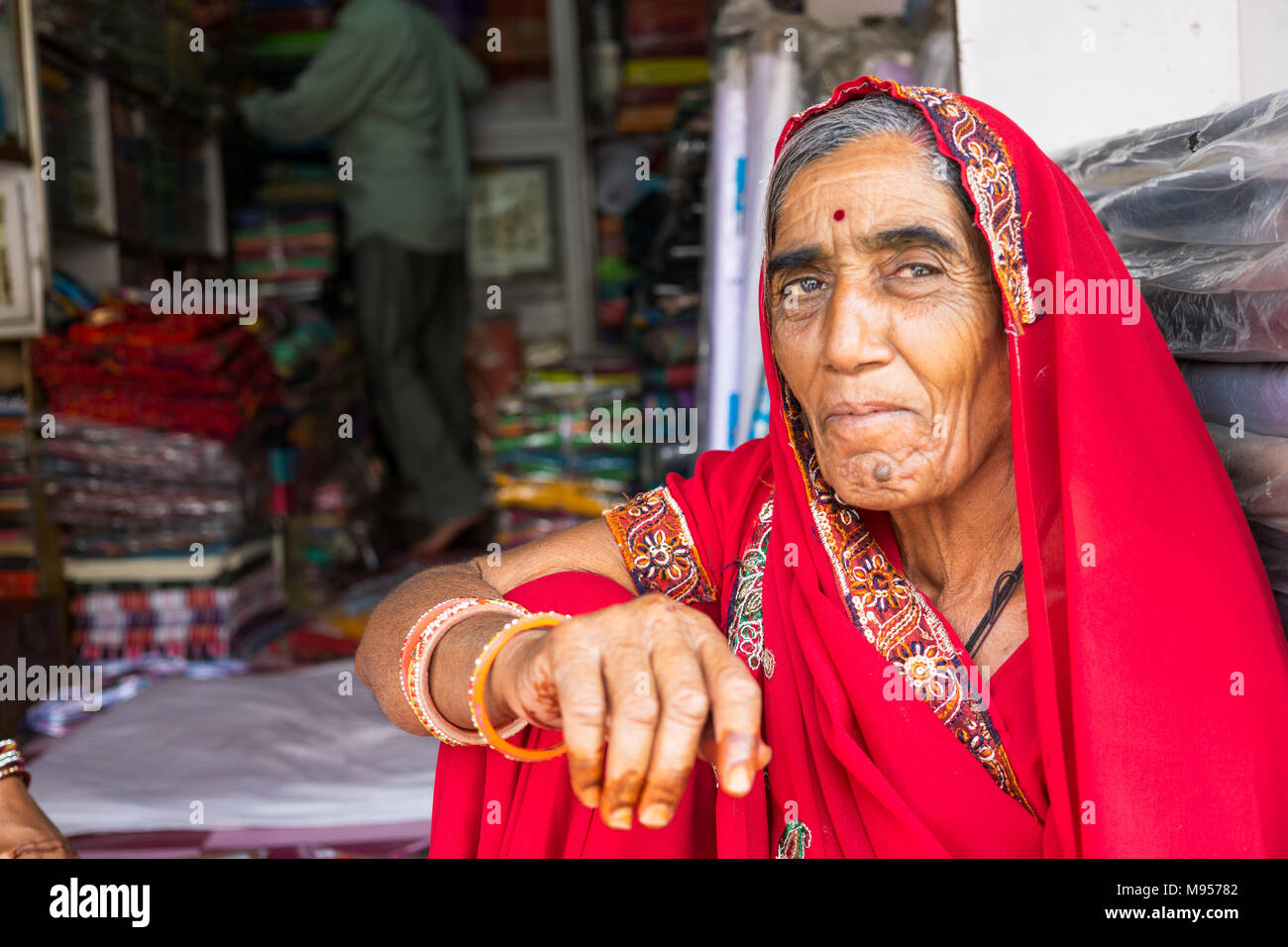 Mandawa, Indien - 24. Februar 2018: Portrait eines älteren indischen Frau mit traditionellen Kleid Saree sitzen Infornt ein Textilgeschäft in Mandawa, Rajas Stockfoto