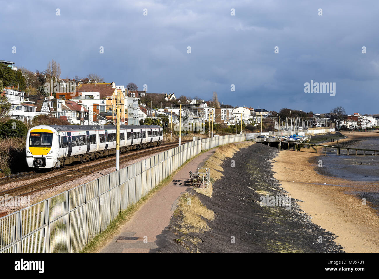 C2C-Eisenbahn Zug vorbei Thames Estuary am Strand Chalkwell, Southend On Sea, Essex. Klasse 357 Elektrischer Triebzug von Meer und Strand. Yachten Stockfoto