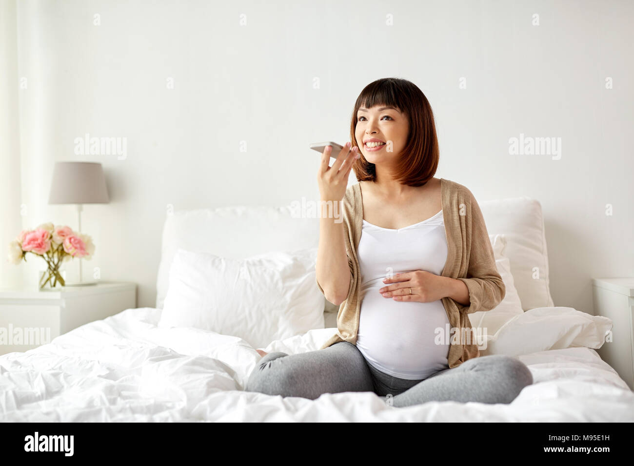 Schwangere Frau mit Voice-Recorder auf smartphone Stockfoto