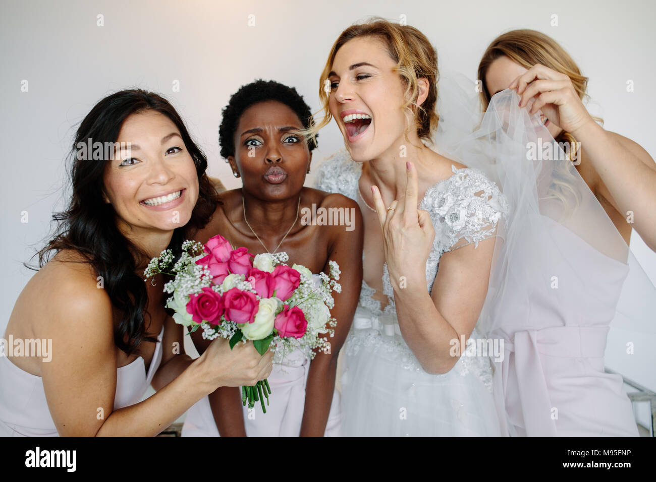 Portrait von fröhlichen Brautjungfern mit der Braut in das Zimmer am Morgen. Wunderschöne Braut im weißen Kleid Spaß mit schönen Brautjungfern in heißem Stockfoto