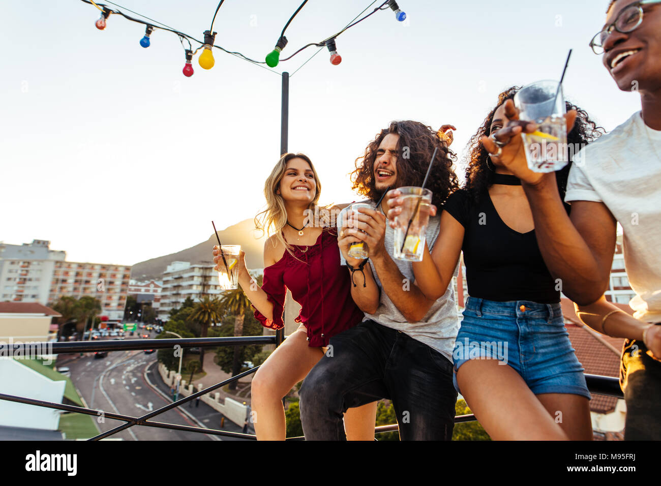 Junge Leute feiern auf der Terrasse bei einem Drink. Gemischten rennen Männer und Frauen einen Drink auf der Dachterrasse. Stockfoto