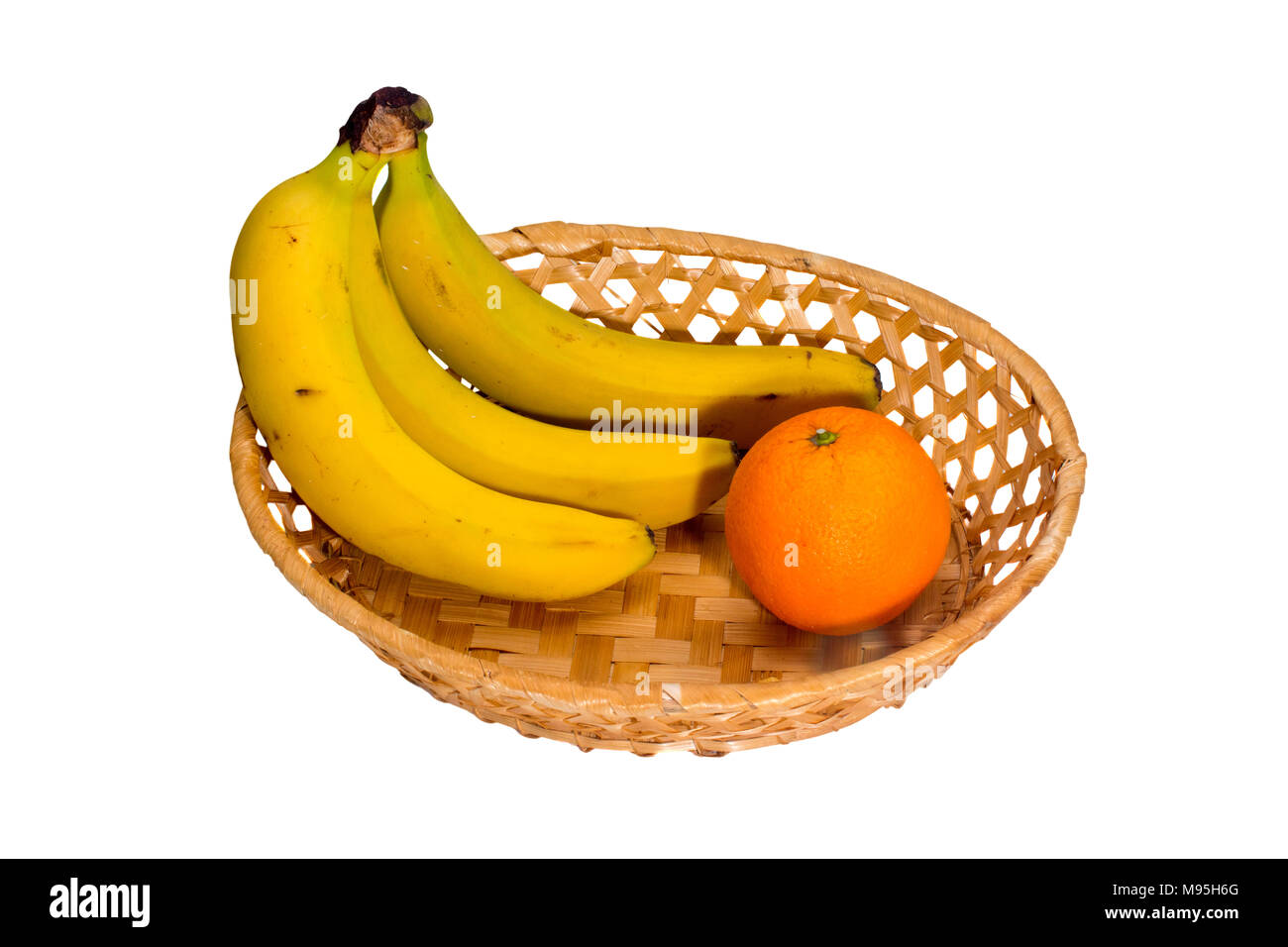 Bild drei Bananen und eine Orange in einem wicker Platte Stockfoto