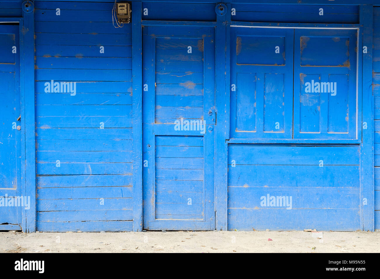 Vorderansicht eines blau lackierten Holz- Haus mit geschlossener Tür-, Fenster- und Shutter - Stockfoto