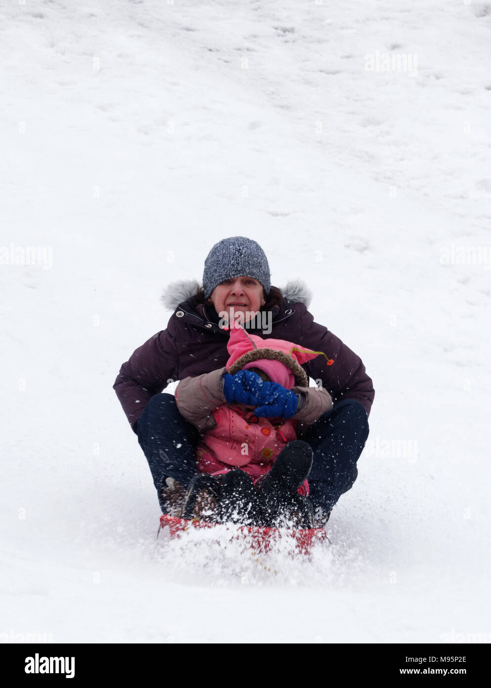 Großmutter schaut erschrocken und Grand-Tochter deckt Ihre Augen beim Schlittenfahren in Québec, Kanada Stockfoto
