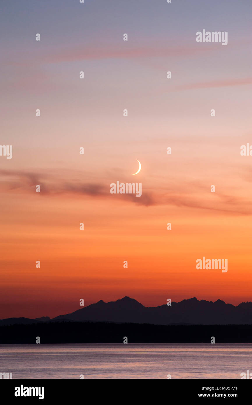 Schönen Sonnenuntergang über Olympischen Berge und Puget Sound mit Halbmond. Stockfoto