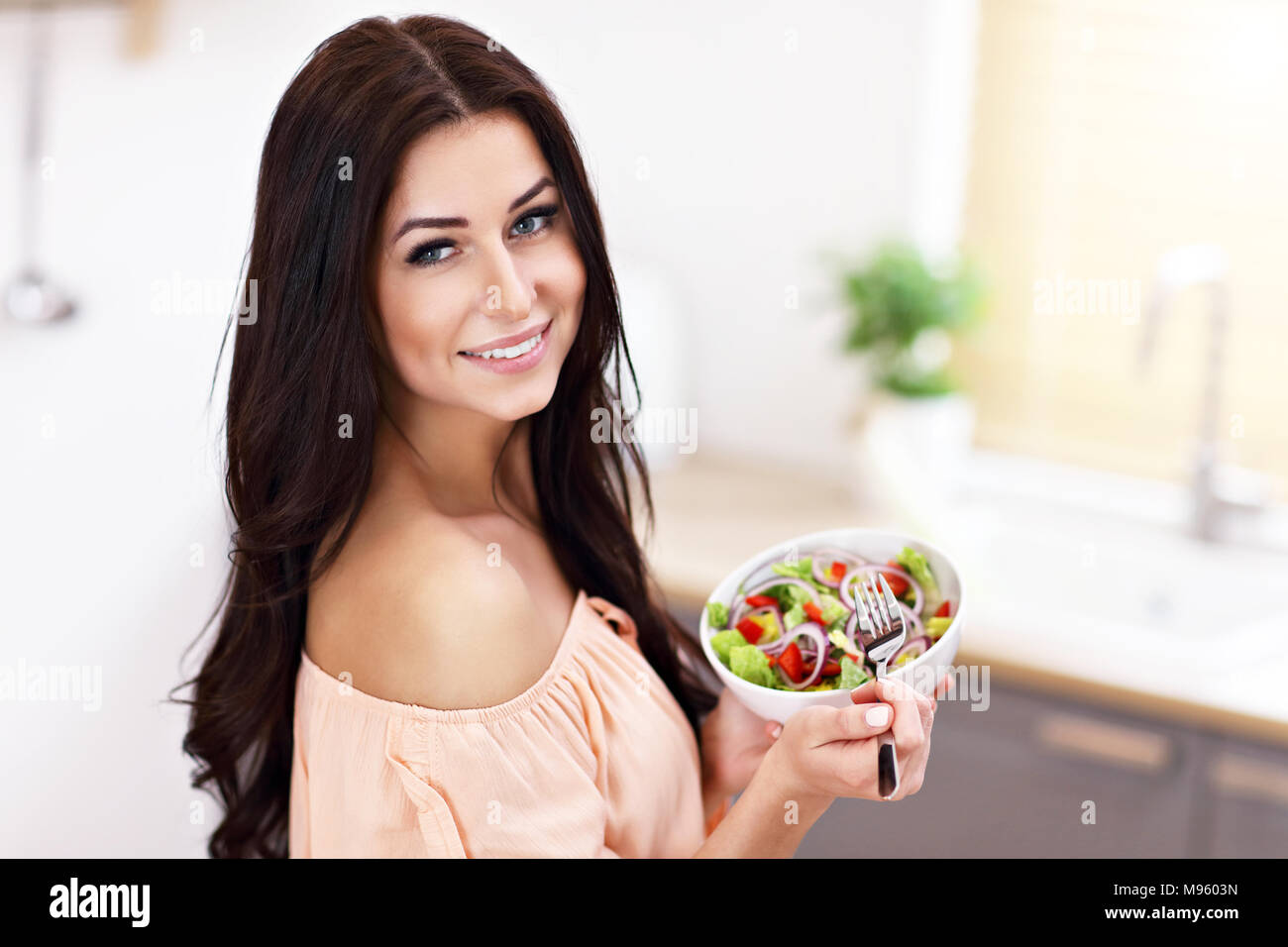 Glückliche Frau Zubereitung Salat in der modernen Küche Stockfoto