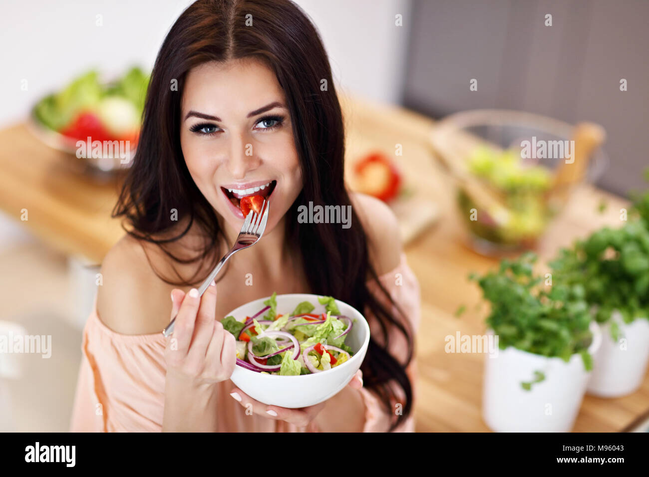 Glückliche Frau Zubereitung Salat in der modernen Küche Stockfoto
