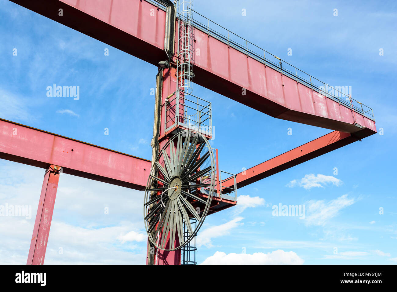 Ansicht von unten von einem roten Behälter Portalkran für den Umgang mit trockenen Cargo Container in der intermodalen Terminals ein Flusshafen, gegen den blauen Himmel. Stockfoto