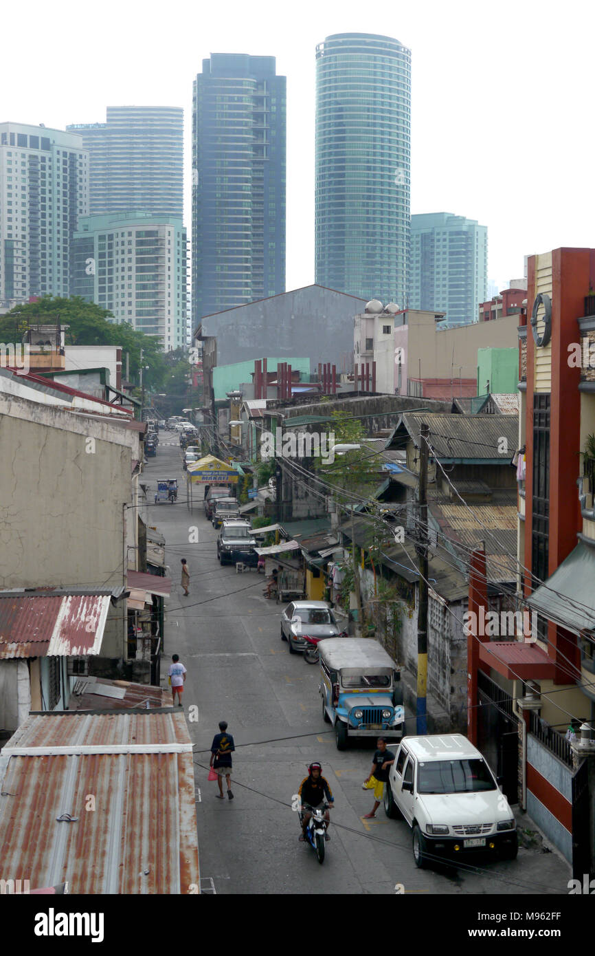 Blick hinunter eine alte Straße überschattet von Hochhäusern, in Manila. Stockfoto