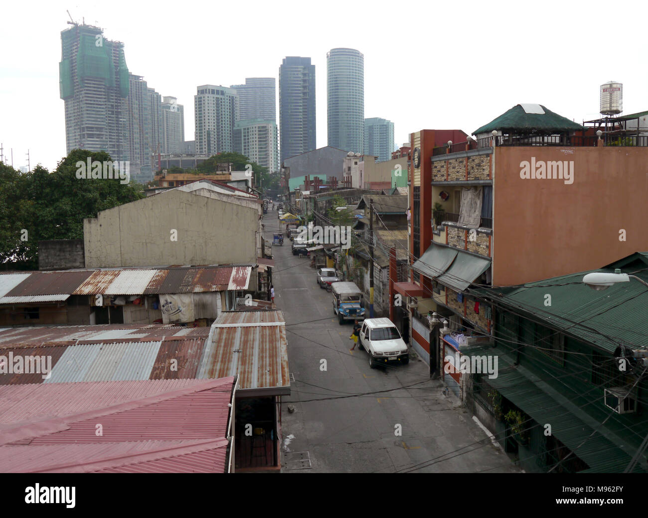 Blick hinunter eine alte Straße überschattet von Hochhäusern, in Manila. Stockfoto