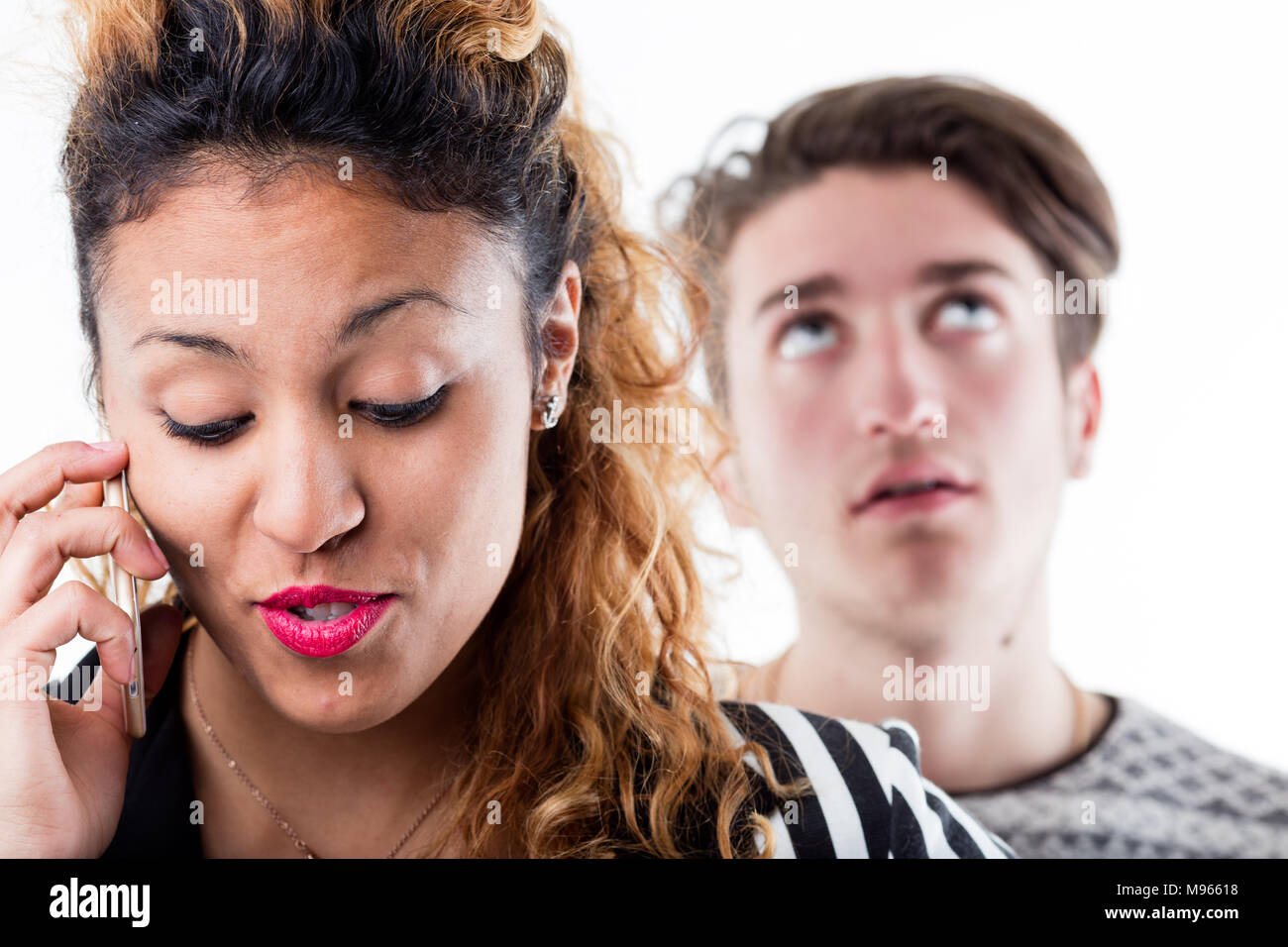 Gesprächige Frau am Telefon sprechen, während ungeduldige Mann im Hintergrund Stockfoto