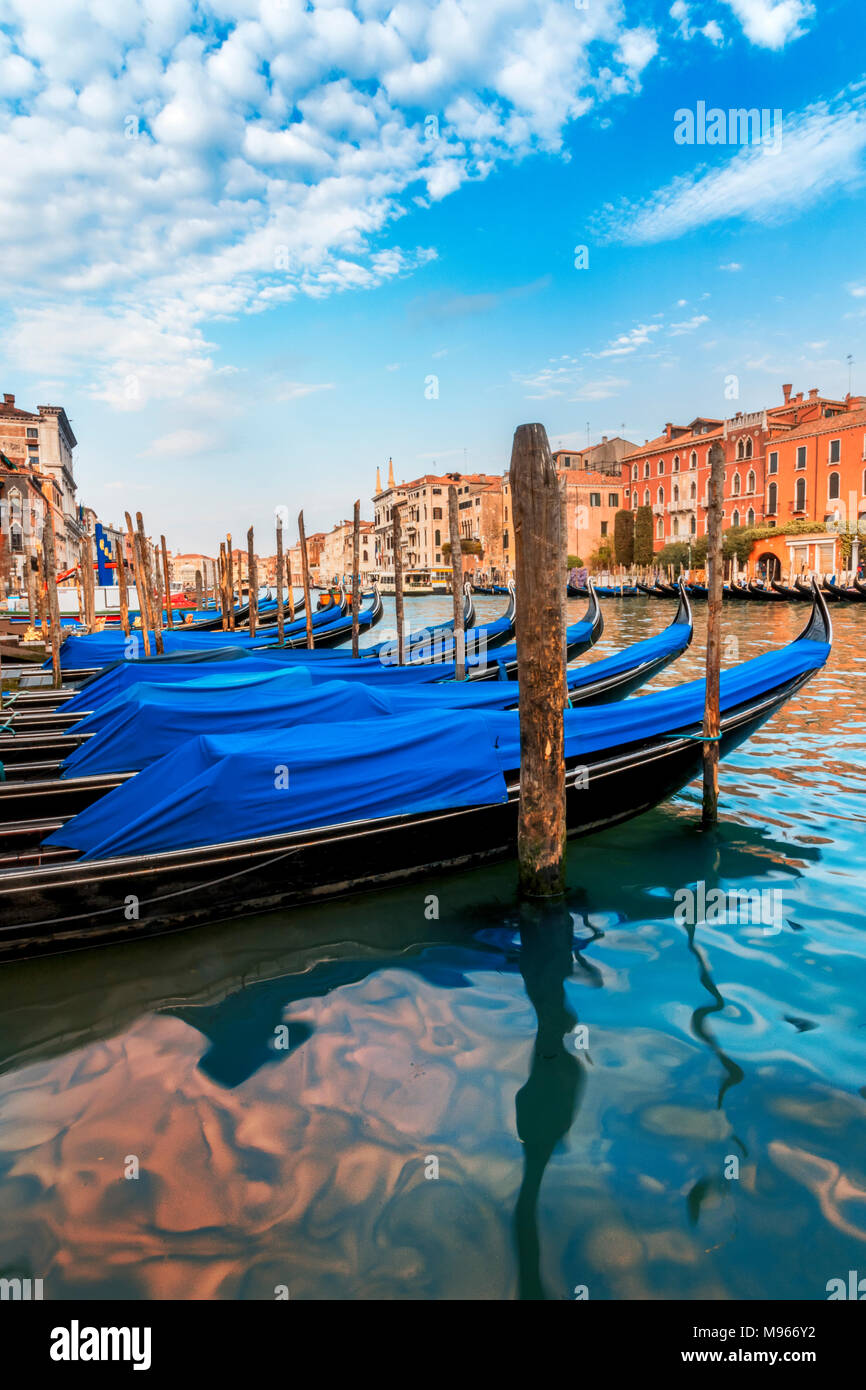 Überdachte Gondeln zu Beiträge in Venedig mit blauem Himmel und abstrakte Überlegungen im Kanal von Gebäuden auf jeder Seite umgeben gebunden Stockfoto