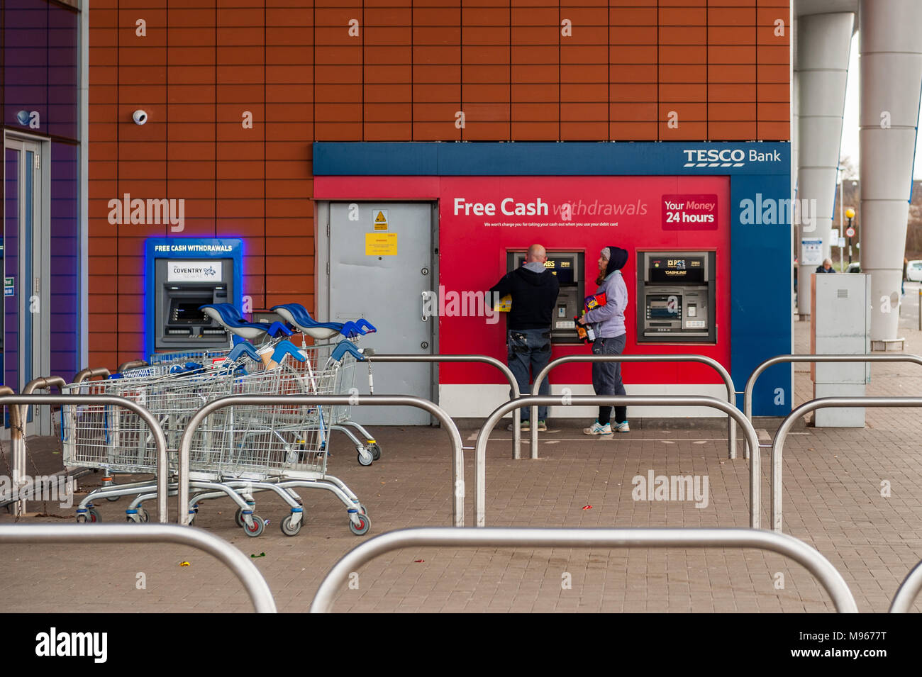 Leute Geld aus einem Tesco ATM in der Arena Retail Park, Coventry, West Midlands, UK. Stockfoto