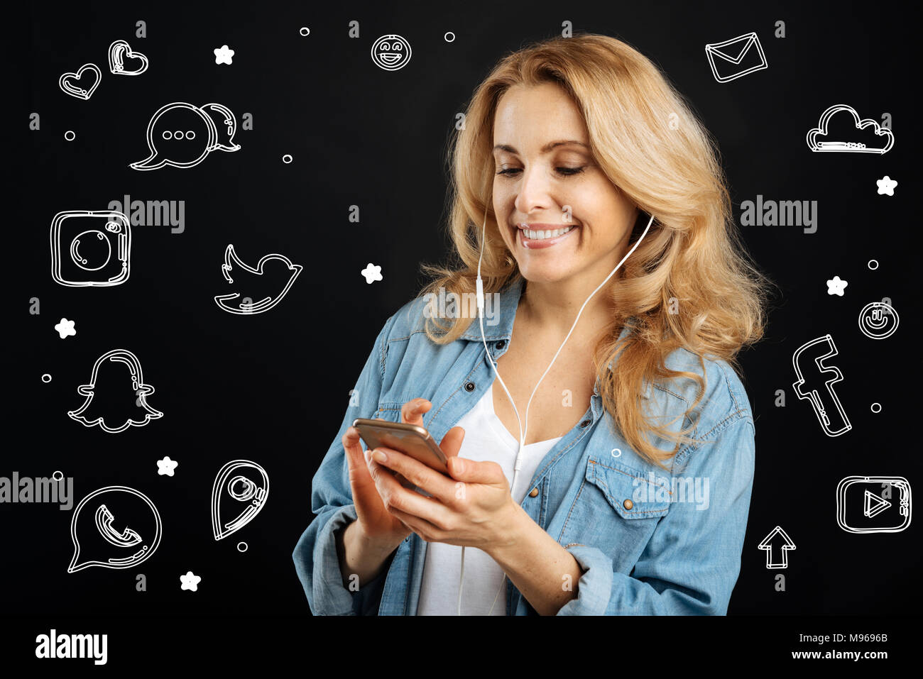Lächelnde Frau mit einem Smartphone und das Hören von Musik in Ihrer Kopfhörer Stockfoto
