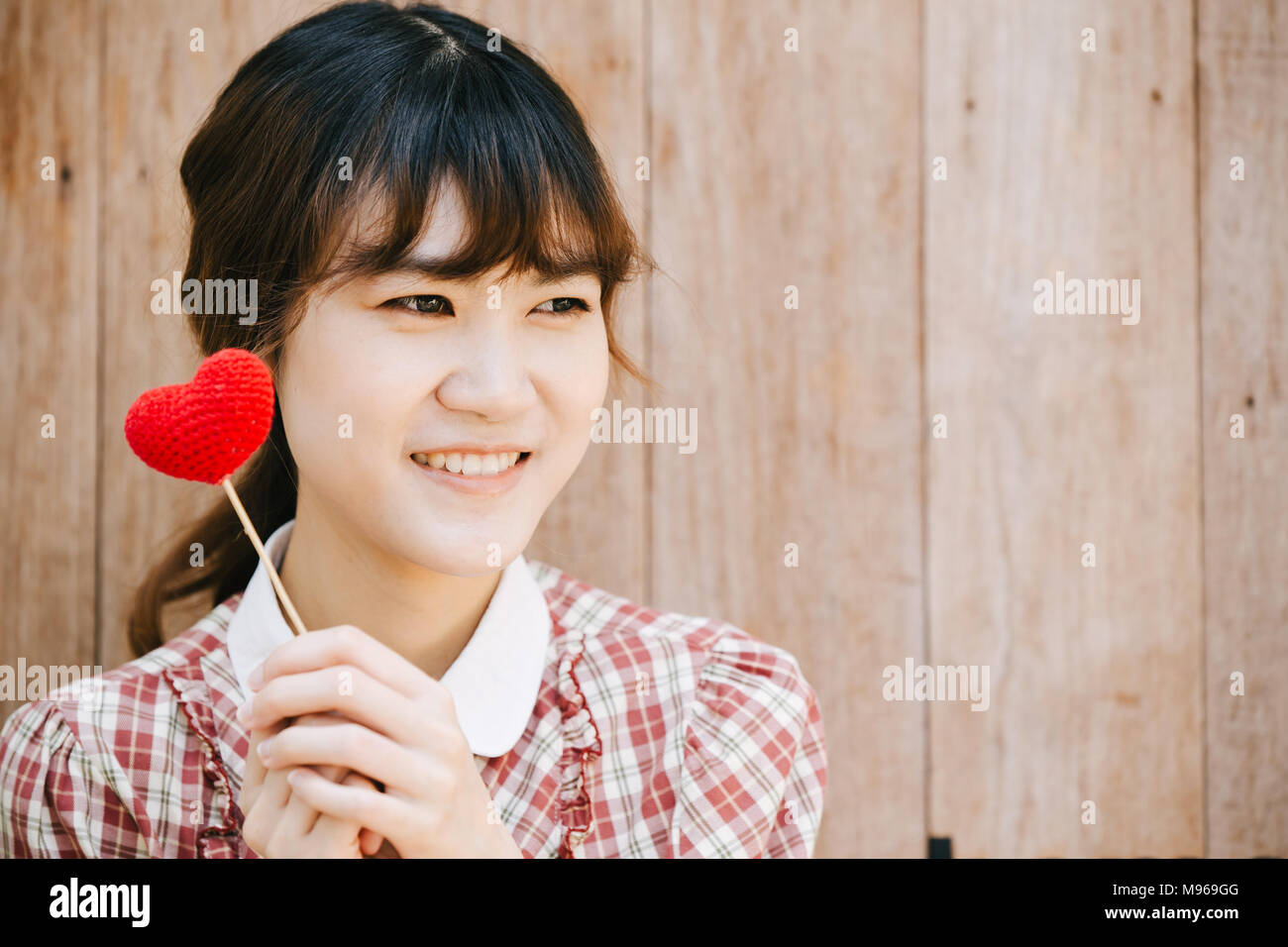 Nette junge Asien Frau, die roten Herzen auf Holz- hintergrund Vintage colortone Stockfoto