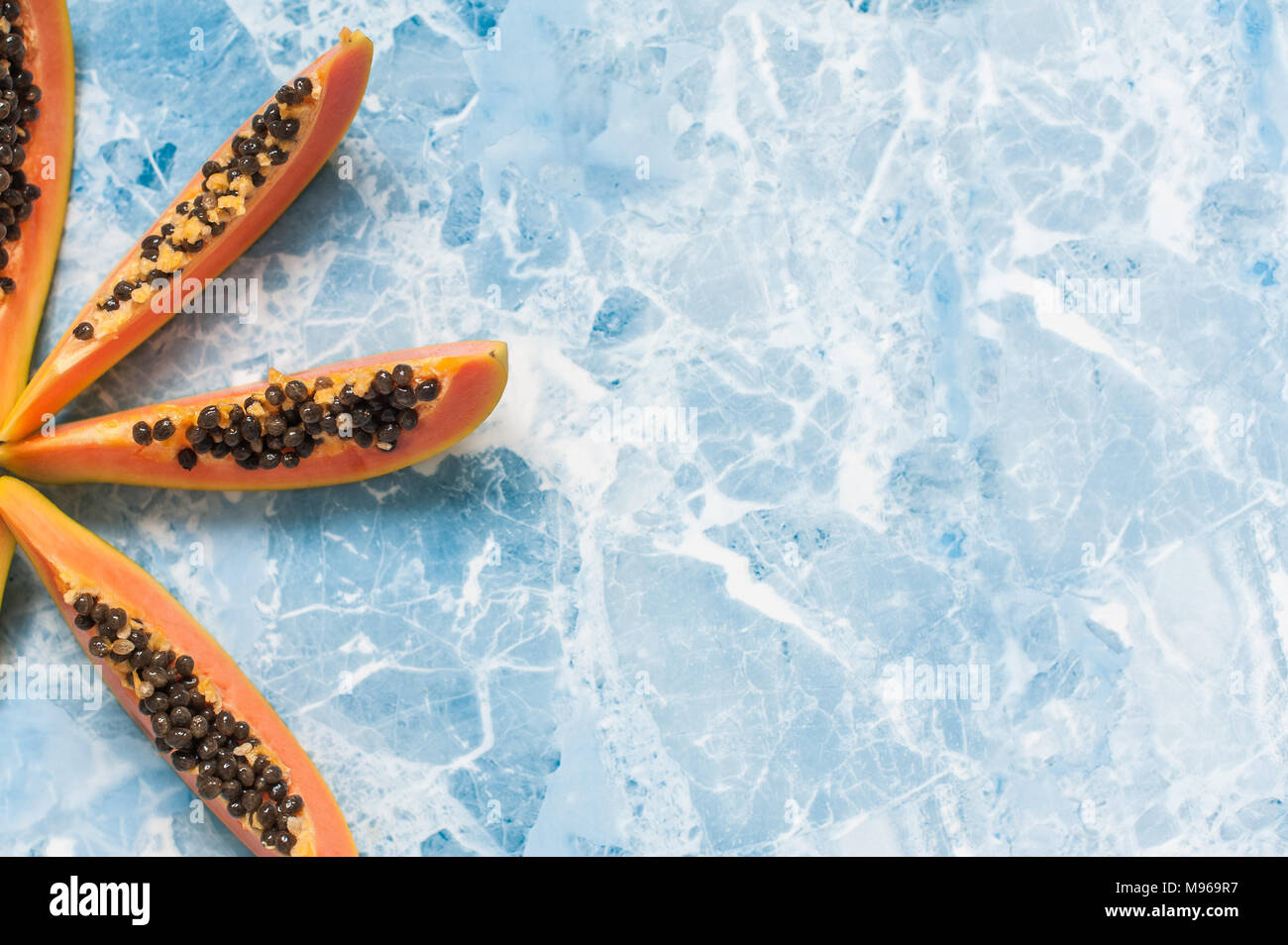 Saftige Scheiben reife Papaya auf blauem Hintergrund. Exotische Früchte, gesundes Essen. Stockfoto
