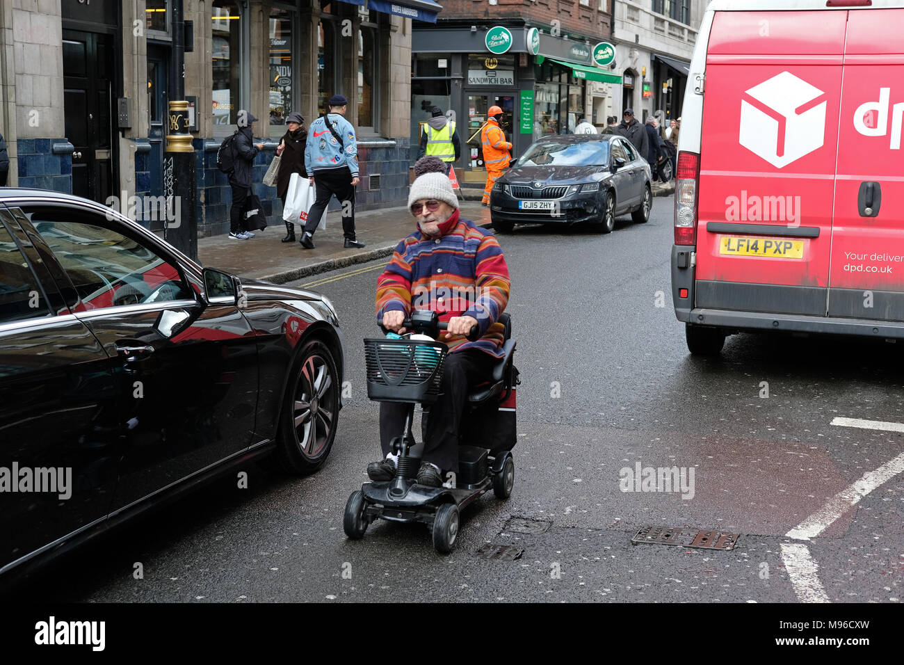 Mann auf einem Mobilität scooter in London in der Nähe von Autos. Stockfoto