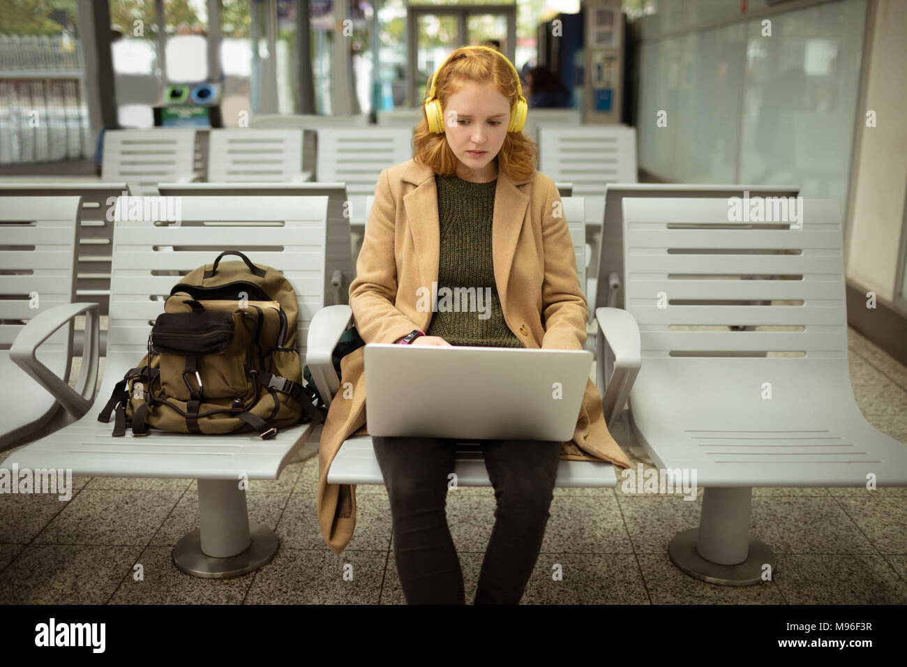 Junge Frau Auflistung zu Musik während der Arbeit am Laptop Stockfoto