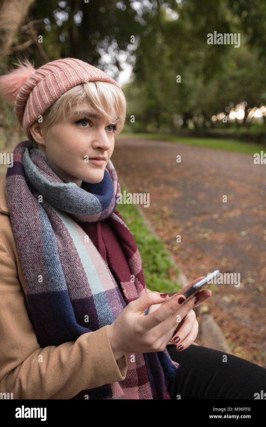 Frau in warme Kleidung mit Handy im Park Stockfoto