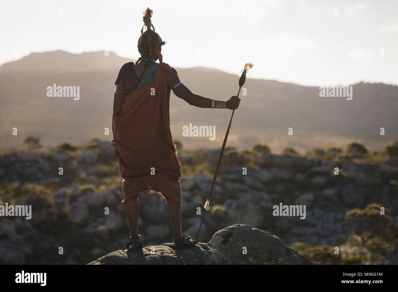 Rückansicht der Masai Mann mit Stock auf Felsen Stockfoto