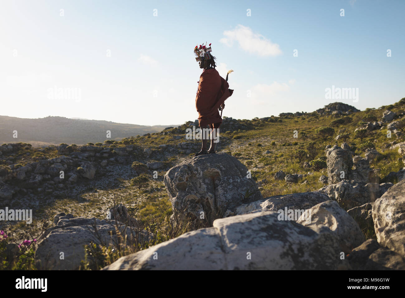 Masai Mann mit Stock auf Felsen Stockfoto