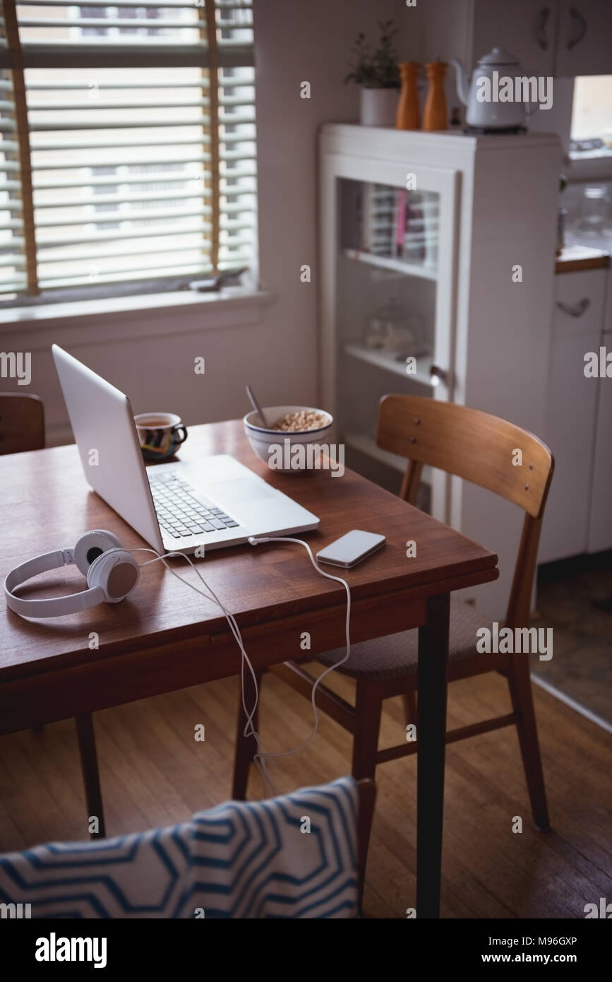 Laptop mit Frühstück und Kaffee auf Esstisch Stockfoto