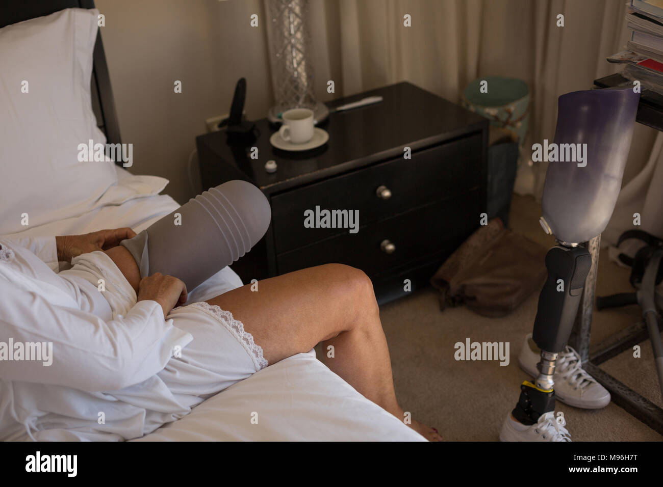 Frau mit Prothese Socken tragen im Schlafzimmer Stockfoto