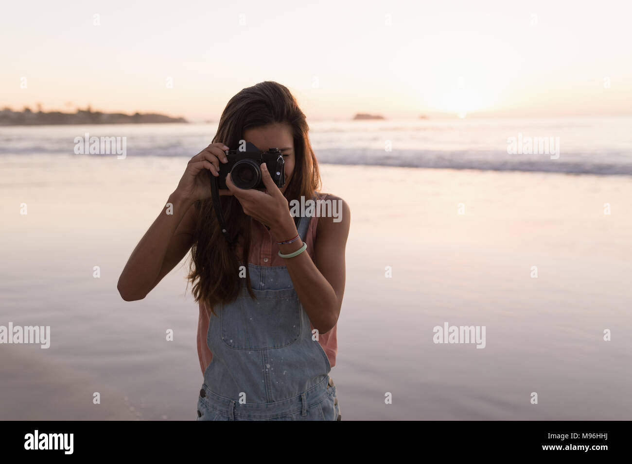 Frau, die Fotos mit der Kamera am Strand Stockfoto
