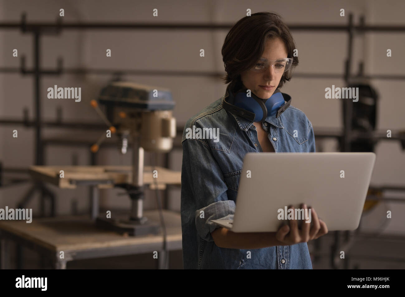 Weibliche Schweißer mit Laptop in der Werkstatt Stockfoto
