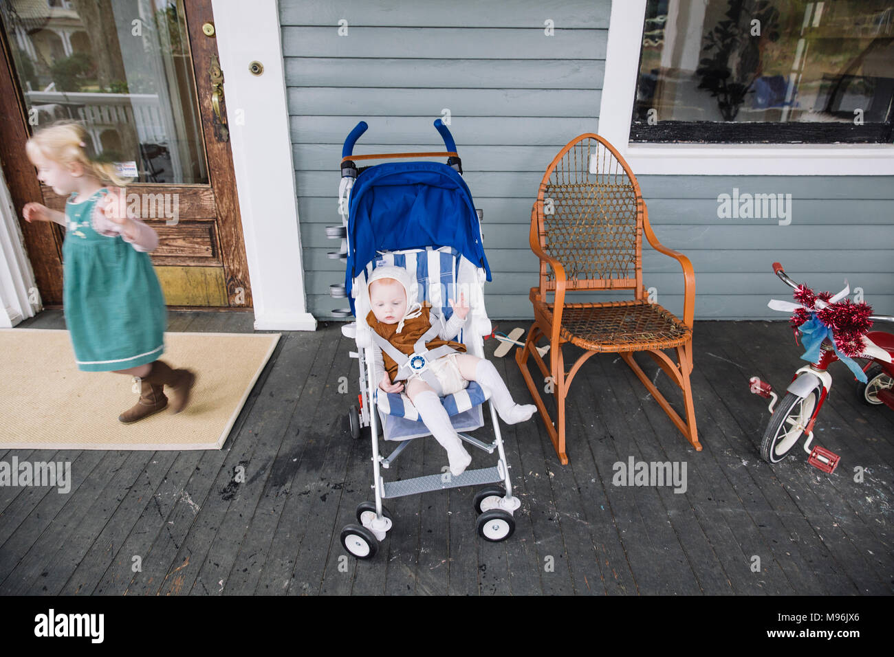 Mädchen mit Dreirad neben Baby blau Kinderwagen Stockfoto