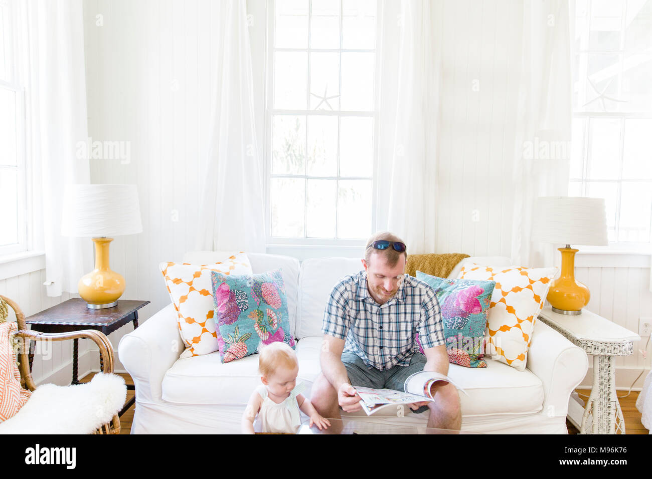 Mann mit Sonnenbrille neben Baby lesen Stockfoto