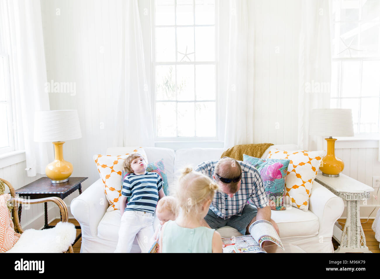 Mann lesen auf dem Sofa mit Kindern um ihn herum Stockfoto