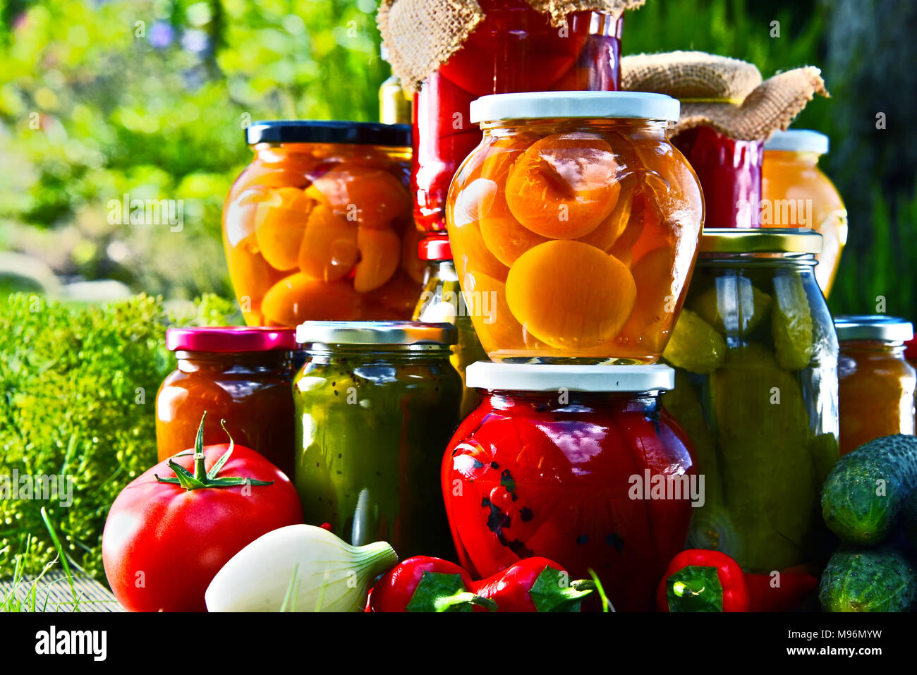 Gläser mit eingelegtem Gemüse und Obst im Garten. Marinierte Lebensmittel. Stockfoto
