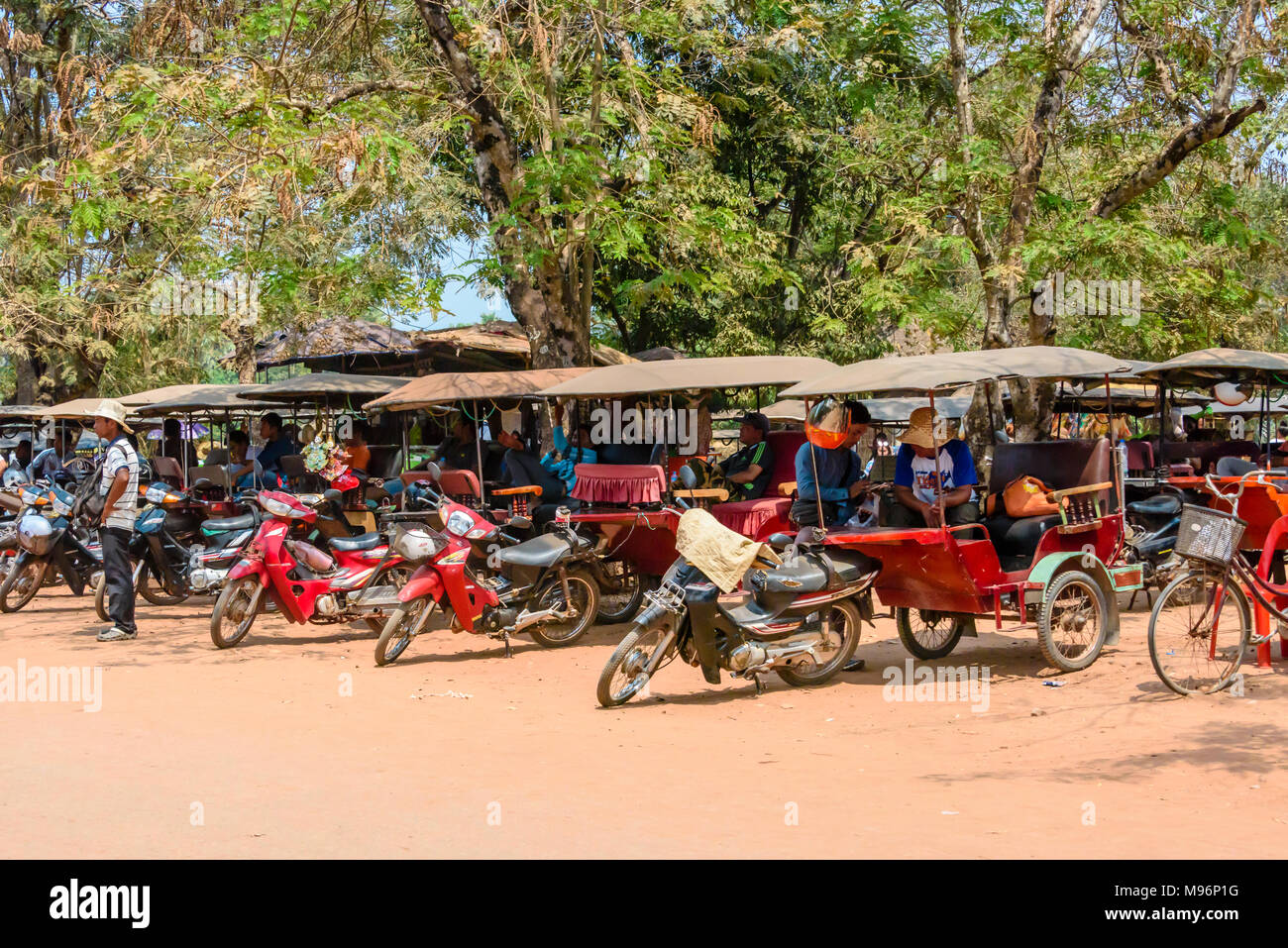 Treiber warten mit ihren geparkten Tuk-tuks (Motorräder mit Anhänger als Taxi eingesetzt) in Kambodscha. Stockfoto