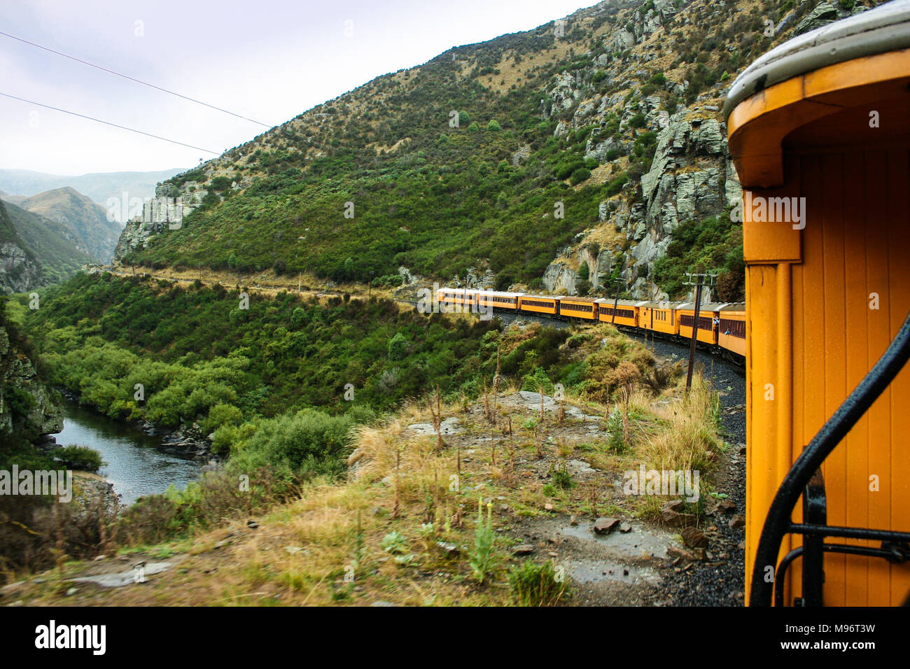 Blick auf eine helle gelbe Zug obwohl die Hügel, Täler und Schluchten von Neuseeland Stockfoto
