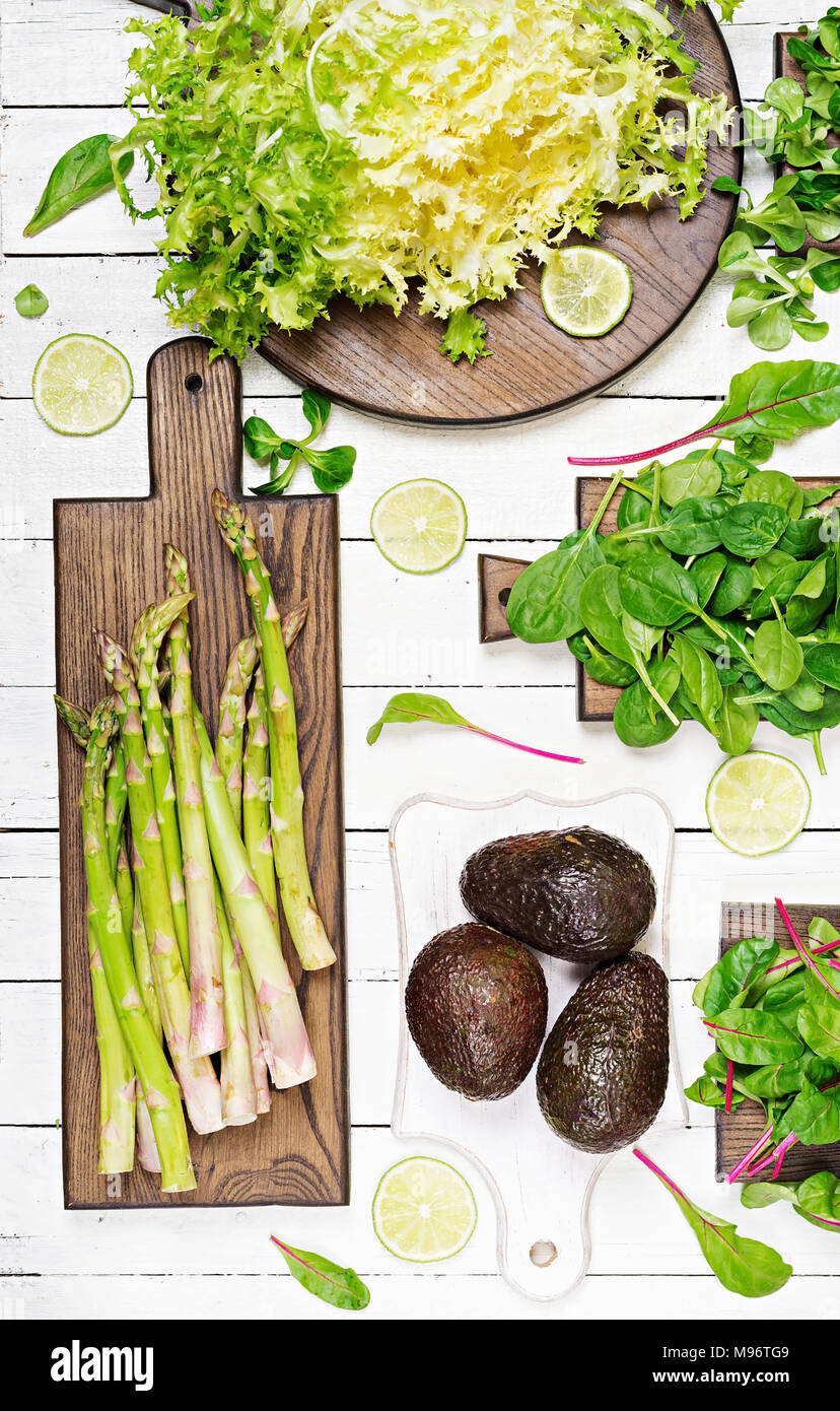 Grüne Kräuter, Spargel und schwarz Avocado auf weißem Holz- Hintergrund. Ansicht von oben. Flach Stockfoto