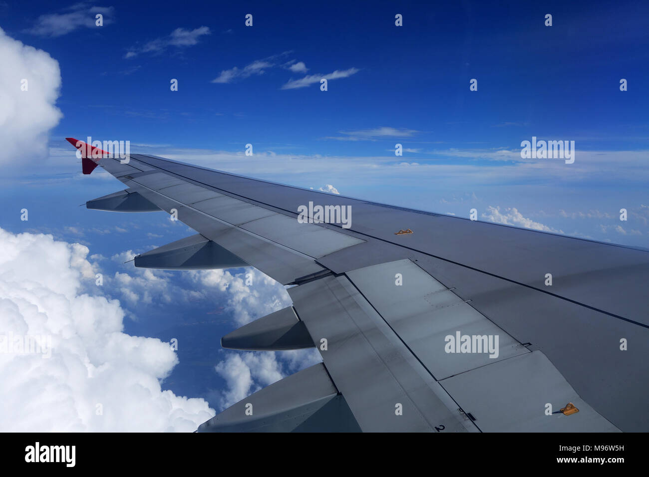 Blick vom Flugzeug über dem Flügel zu Wolken und Meer unter. Stockfoto