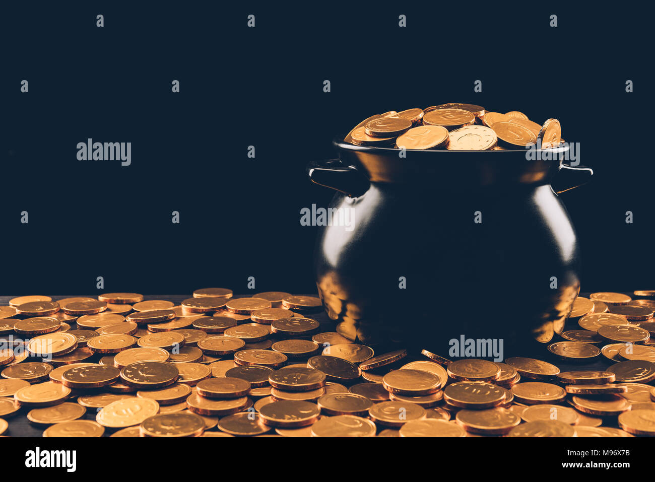 Schwarzer Topf mit goldenen Münzen auf Schwarz, st patricks day Konzept isoliert Stockfoto