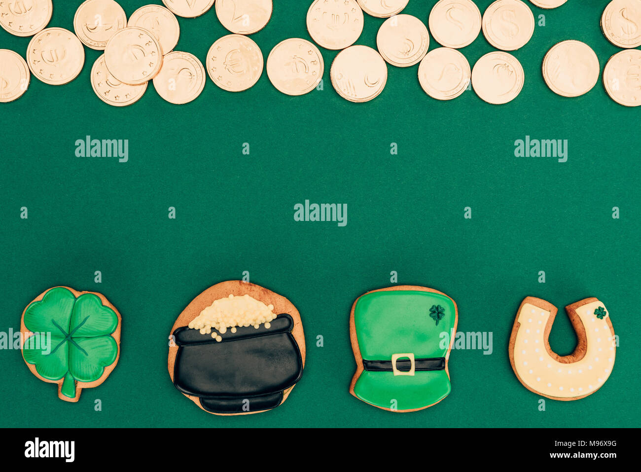 Blick von oben auf die Vereisung cookies und goldenen Münzen auf Grün, st patricks day Konzept isoliert Stockfoto