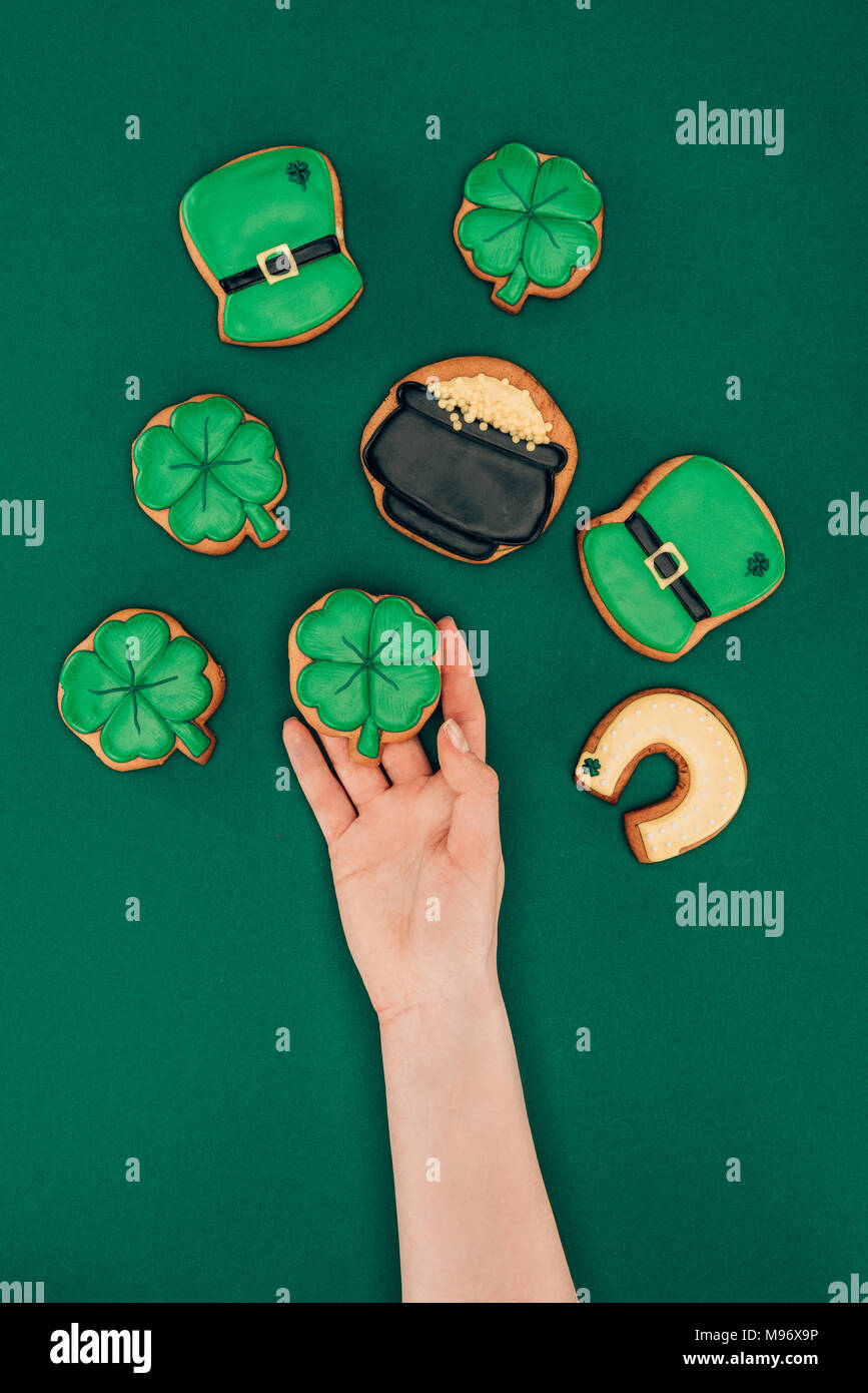 Zugeschnittenes Bild der Frau mit Zuckerglasur Cookies auf Grün, st patricks day Konzept isoliert Stockfoto