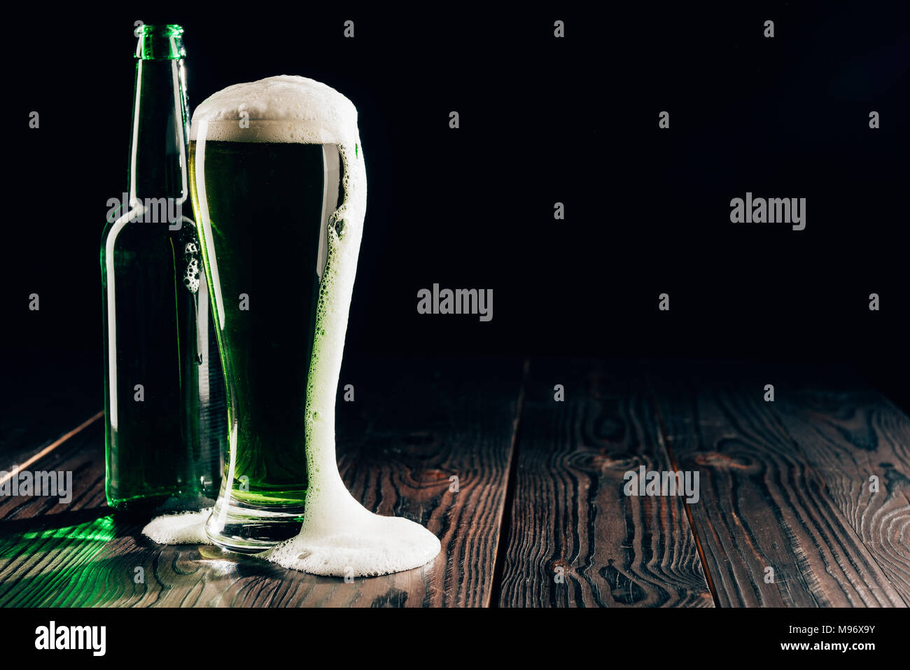 Glas und Flasche grün Bier mit Schaum auf Tisch, st patricks day Konzept Stockfoto