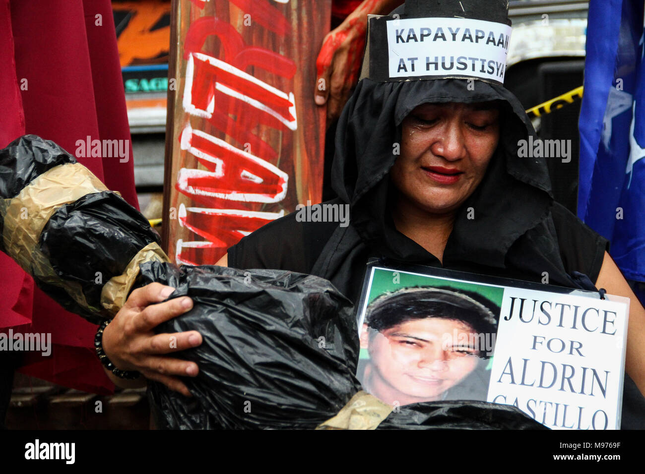 Manila, Philippinen. 23. März, 2018. Nanette Castillo trägt einen falschen Körper eines außergerichtlichen Tötung in Plaza Miranda, wissen sie, wie ihr Sohn, Aldrin Castillo, die im Oktober 2017 von noch nicht identifizierten Angreifer getötet wurde. Aktivisten zugeschlagen Duterte für den angeblichen Doppelzimmer Standard in seinem Krieg gegen Drogen, das harte Vorgehen gegen die Aktivisten, und die jüngste Ausweisung von Aktivisten als Terroristen nach dem Malacanang. Der März war ein paar Tage vor der Heiligen Woche gehalten, mit den Demonstranten, die ein Kreuz zu Mendiola, Manila. Credit: SOPA Images Limited/Alamy leben Nachrichten Stockfoto