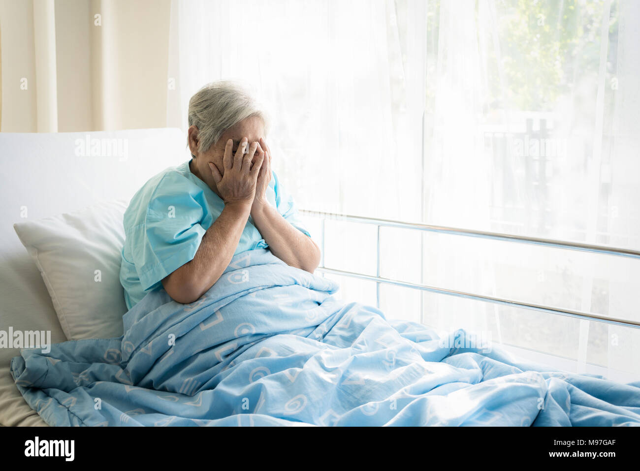 Asiatische gedrückt ältere Frau Patienten liegend auf Bett Blick aus dem Fenster im Krankenhaus. Ältere Frau Patienten ist froh, von der Krankheit erholt. Stockfoto