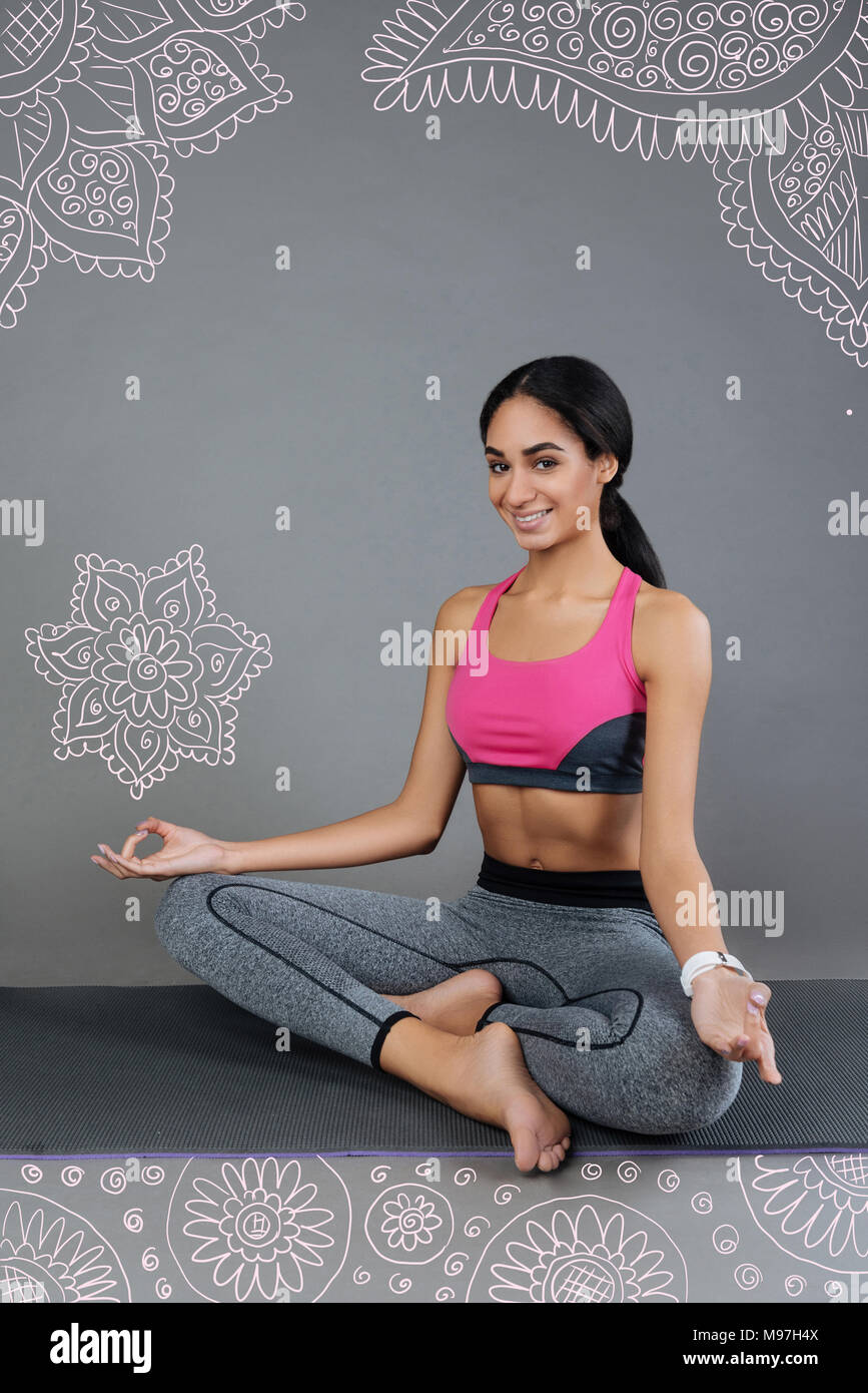 Schöne junge Frau lächelnd, während er auf dem Yoga Matte Stockfoto